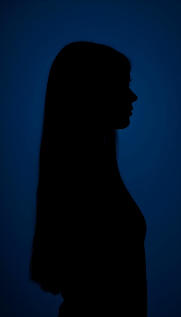 A (((black silhouette of a young girl with long straight hair))), perfect curved female figure, all against a deep blue backdrop, side view.