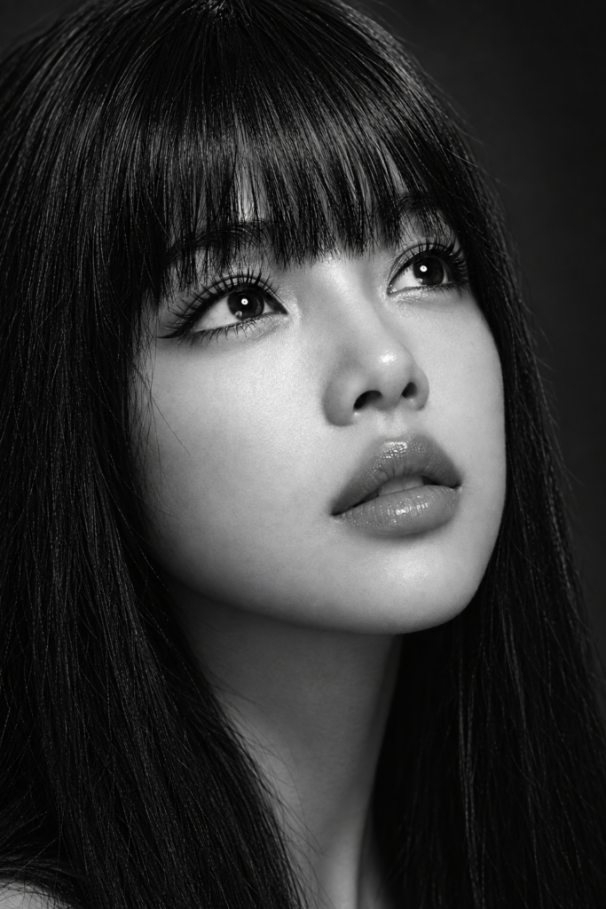 Black and white photorealistic beauty portrait of a young woman with an angelic, delicate face, flawless porcelain-smooth luminous skin, dark deep expressive eyes with long full eyelashes, full kissable lips gently parted, long straight jet-black hair with a straight fringe (bangs) falling just above her eyebrows. Very tight beauty crop from forehead to chin, she looks slightly upward past the camera, chin lifted. Tack-sharp crisp focus on the eyelashes, iris detail and lip texture, fine natural skin detail. Bright soft top light with a clean ring catchlight in the eyes, near-black background, deep blacks and silvery highlights, high-contrast monochrome. 100mm macro beauty look, editorial fashion photography, ultra detailed.